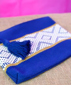Pochette artisanale bleu roi en tissu tissé avec motifs ethniques blancs et pompon décoratif bleu.