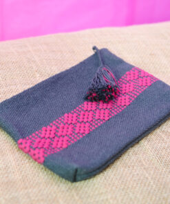 Petite trousse artisanale en tissu gris-bleu avec des motifs géométriques roses brodés et un pompon noir.